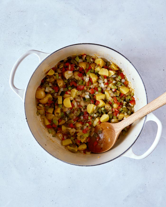 Vegetables added to a stock pot and softening as they cook.