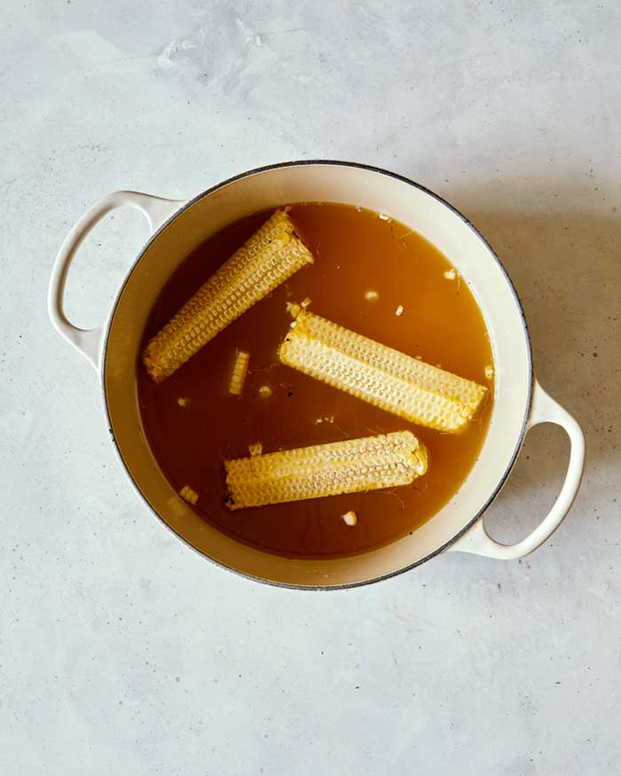 Corn cobs and kernels simmering in stock.