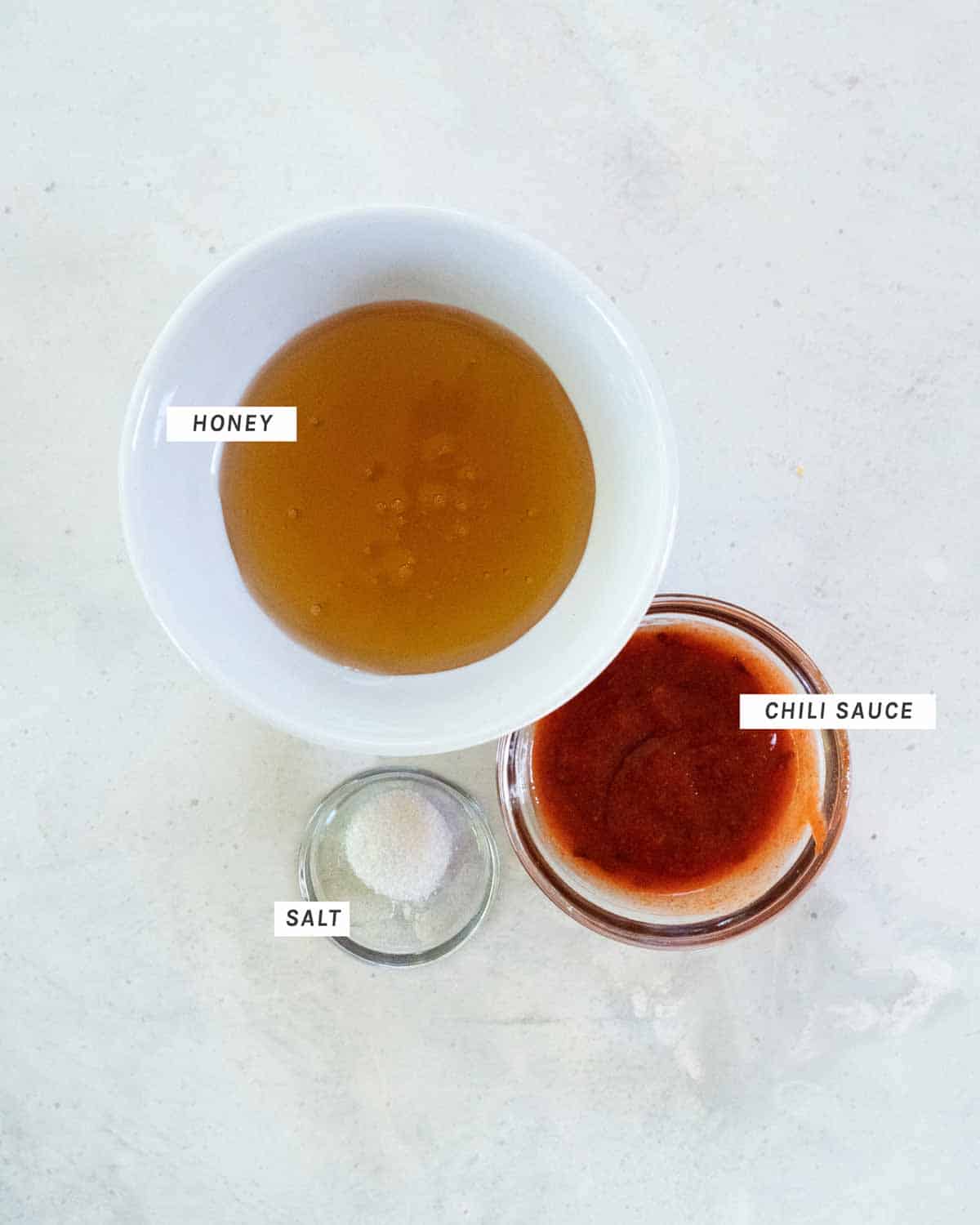 Spicy honey drizzle ingredients in bowls shot overhead.