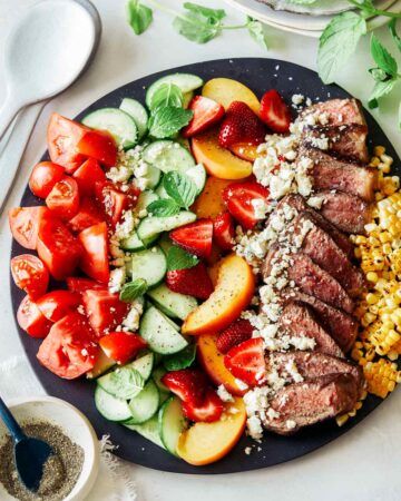 Summer steak salad on a black plate.