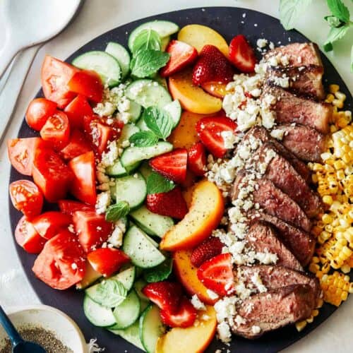 Summer steak salad on a black plate.