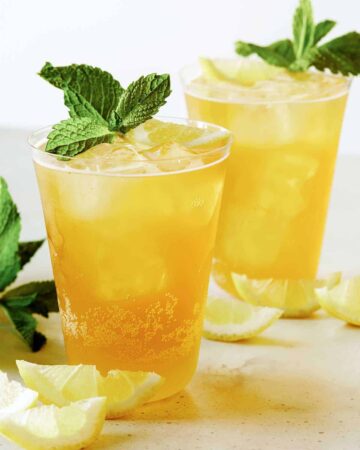 A glass of sparkling lemonade shandy with mint and lemon slice garnish.