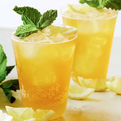 A glass of sparkling lemonade shandy with mint and lemon slice garnish.