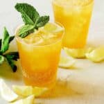 A glass of sparkling lemonade shandy with mint and lemon slice garnish.