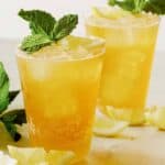 A close up of summer shandy cocktails with fresh mint and lemon wedges.