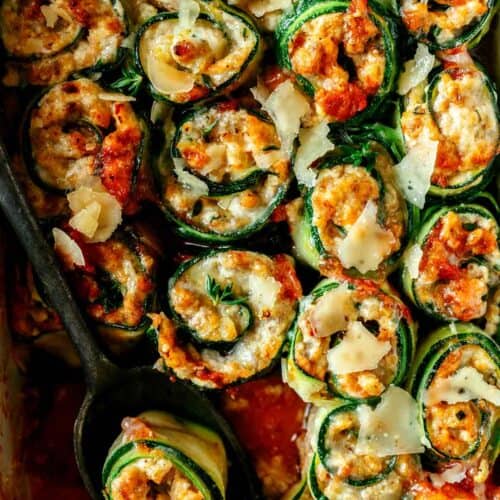 A close up of zucchini lasagna roll ups with a serving spoon.