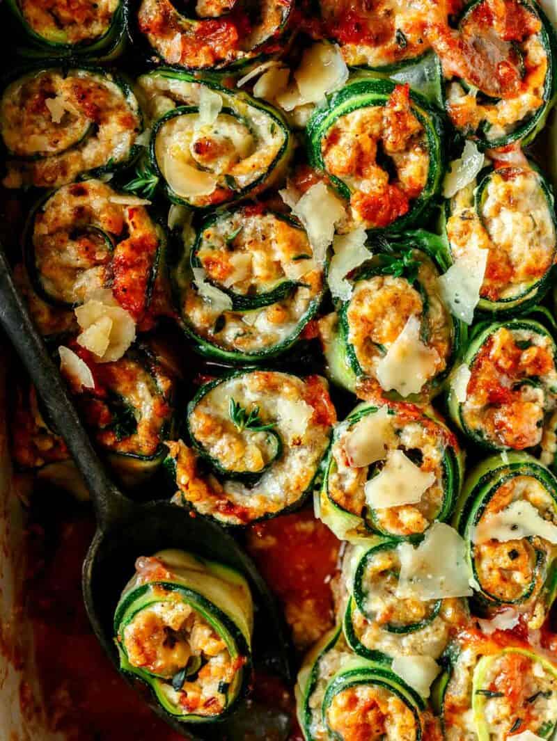 Zucchini lasagna roll ups close up overhead in a baking dish. 