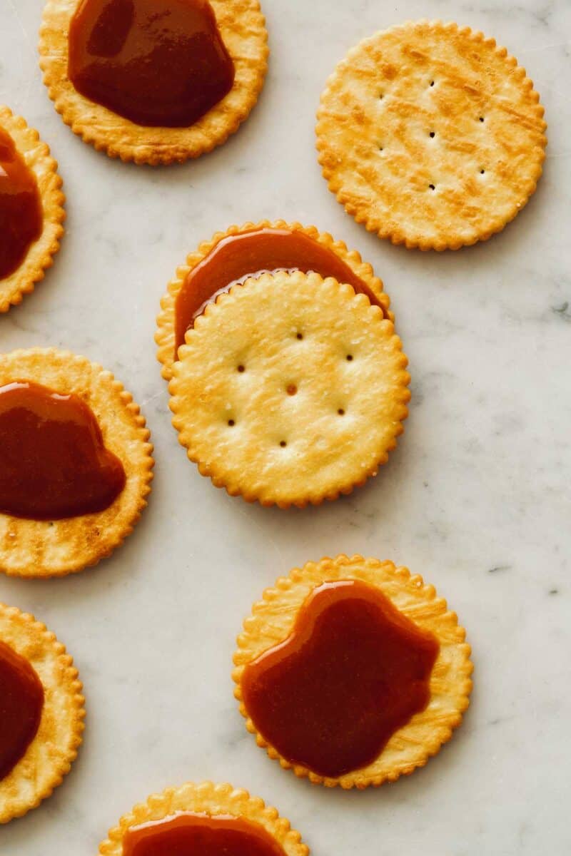 Cajeta on some butter crackers on a kitchen counter.