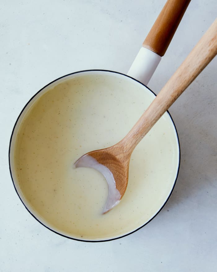 Banana pudding being made in a pot with a wooden spoon.