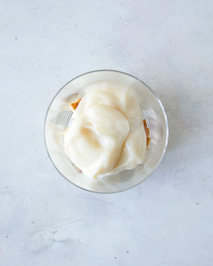 Layering banana pudding ingredients in a cup to make banana pudding.