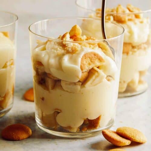 Three cups of banana pudding and one with a spoon in it.