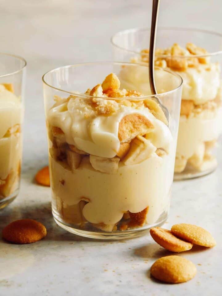 Three cups of banana pudding and one with a spoon in it.