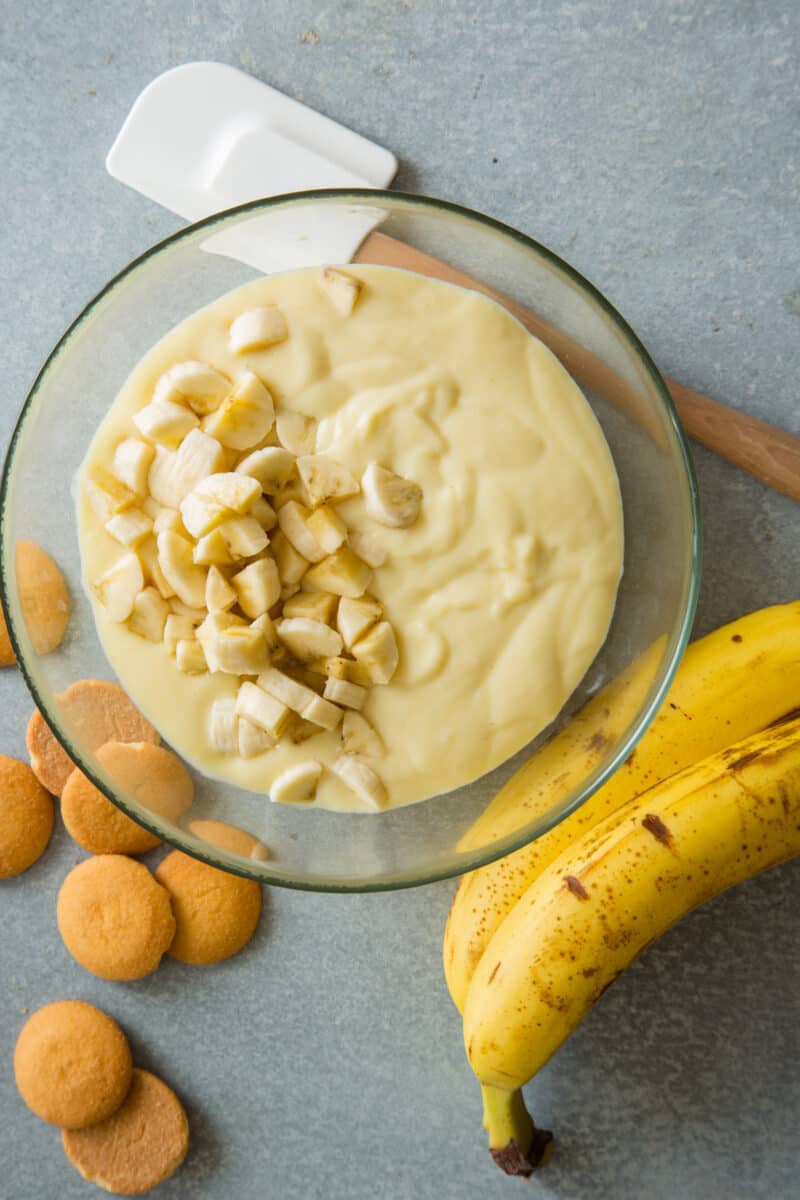 Banana pudding being folded with chunks of bananas.