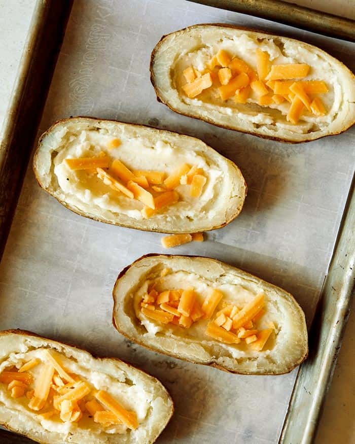 Cheese added into potato halves.