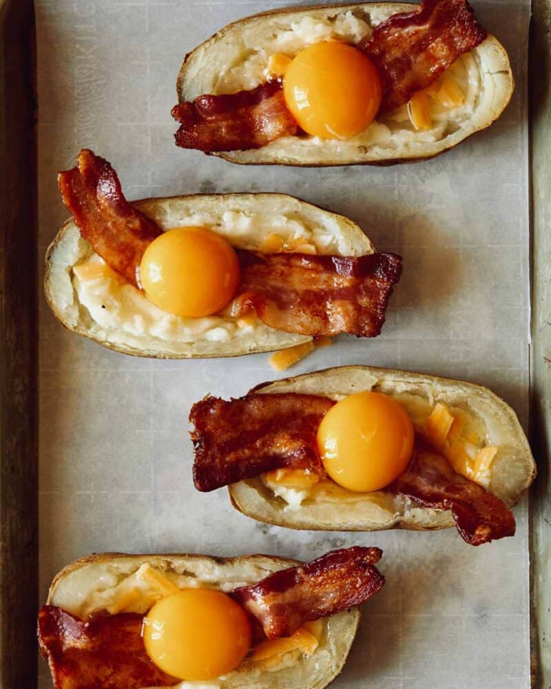 Eggs added to hollowed out potatoes.