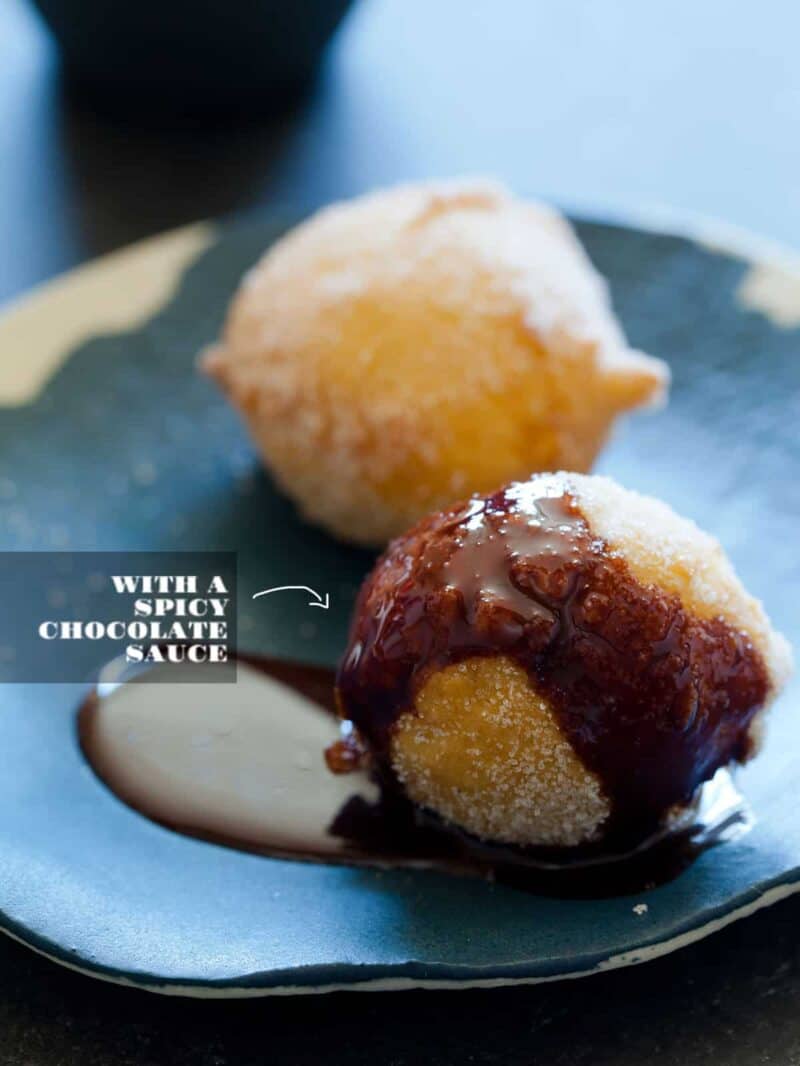 A close up of two bunuelos, one with spicy chocolate sauce and one without.