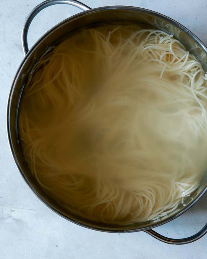Capellini pasta cooking in a pot of water.