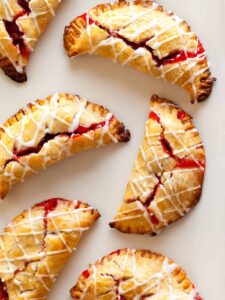 A close up of several cherry hand pies with cherry icing drizzle.