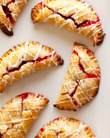 A close up of several cherry hand pies with cherry icing drizzle.