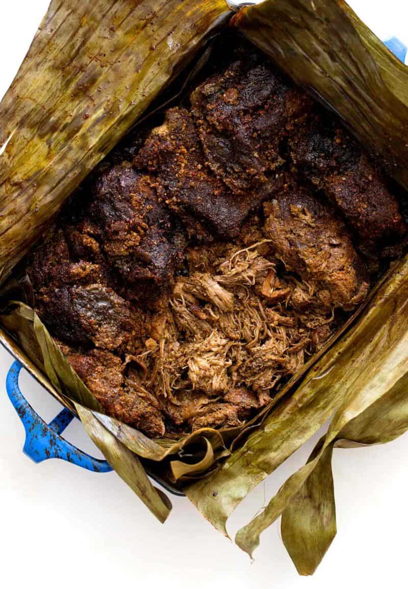 A pan of cochinita pibil in opened banana leaves to reveal the meat.