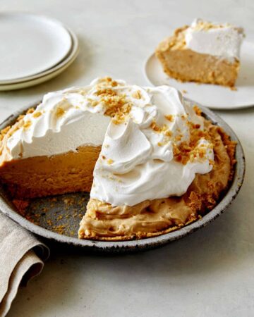 No Bake Peanut Butter Pie with whipped cream on top with a slice taken out.