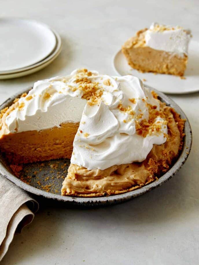 No Bake Peanut Butter Pie with whipped cream on top with a slice taken out.