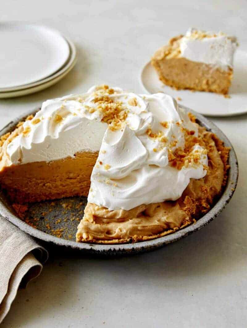 No Bake Peanut Butter Pie with whipped cream on top with a slice taken out. 