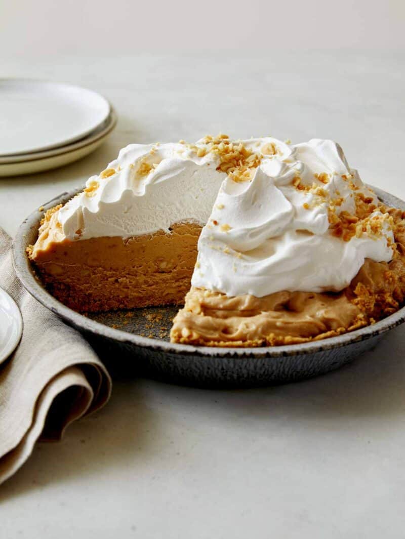 A creamy peanut butter pie with a slice taken out.