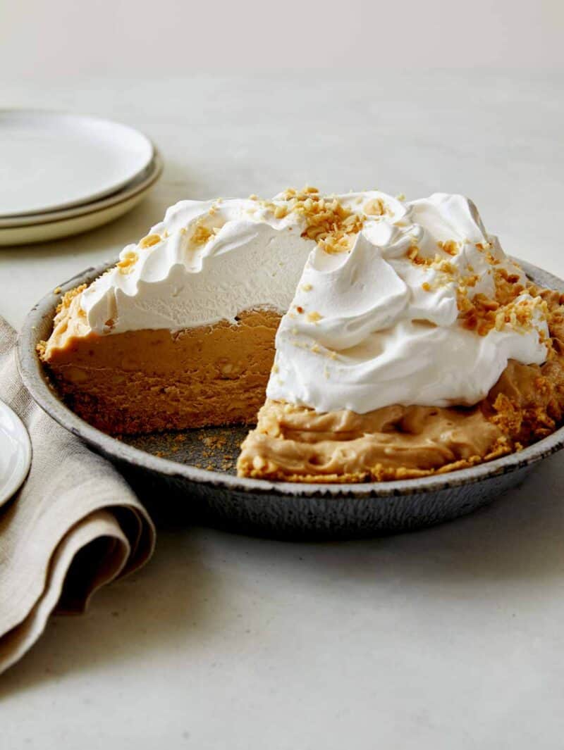 A creamy peanut butter pie with a slice taken out. 