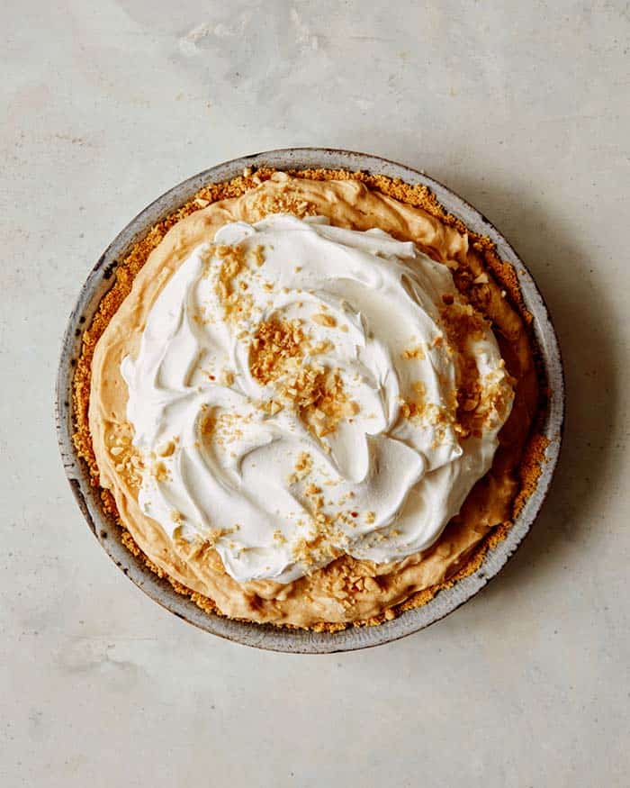 A creamy peanut butter pie with whipped cream on top and nuts.