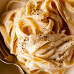 A close up on a bowl of fettuccine alfredo with a fork in it.