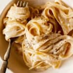 A recipe for one pot fettuccine alfredo in a bowl with a fork.