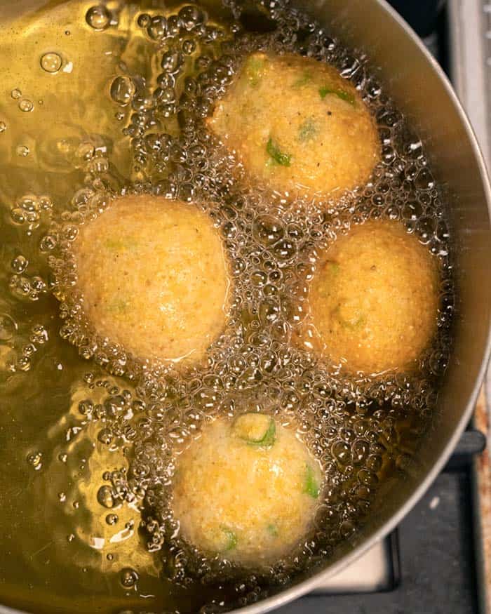 Hush Puppies frying in a pot of oil.