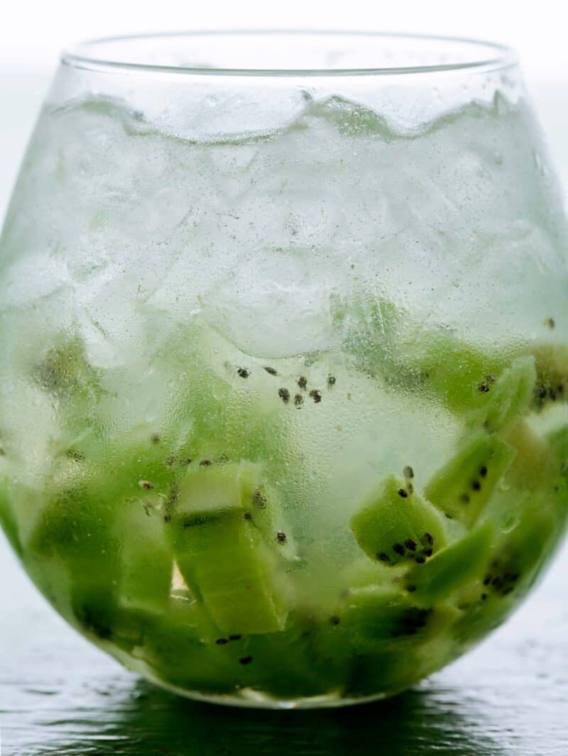 A close up of a glass of kiwi caipiroska.