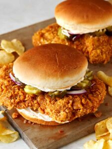 A close up of pork tenderloin sandwiches with potato chips.