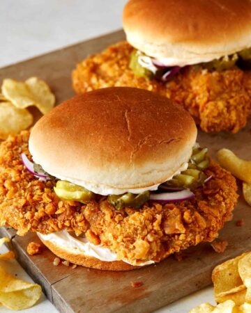 A close up of pork tenderloin sandwiches with potato chips.