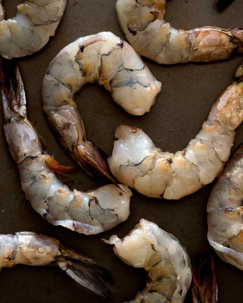 Raw tiger shrimp on a baking sheet.