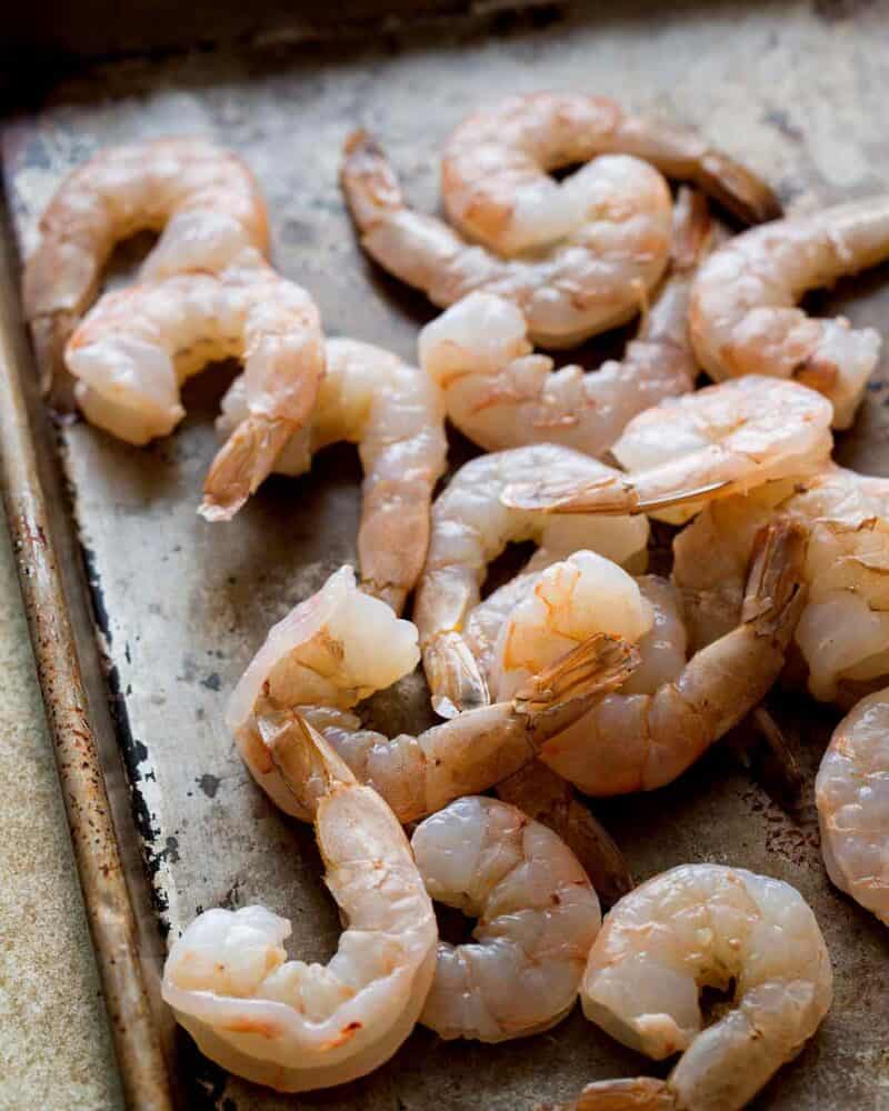 Pink shrimp on a baking sheet.