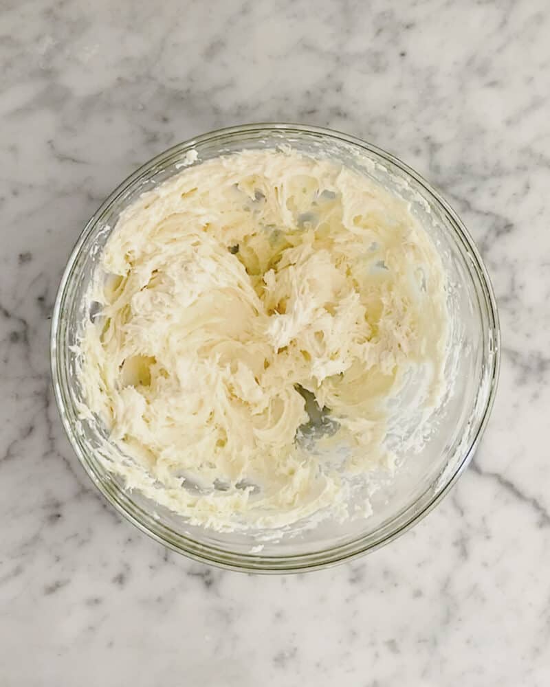 Whipped cream cheese and honey together in a glass bowl.