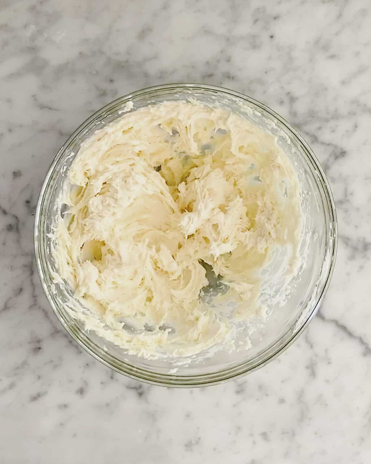 Whipped cream cheese and honey together in a glass bowl. 