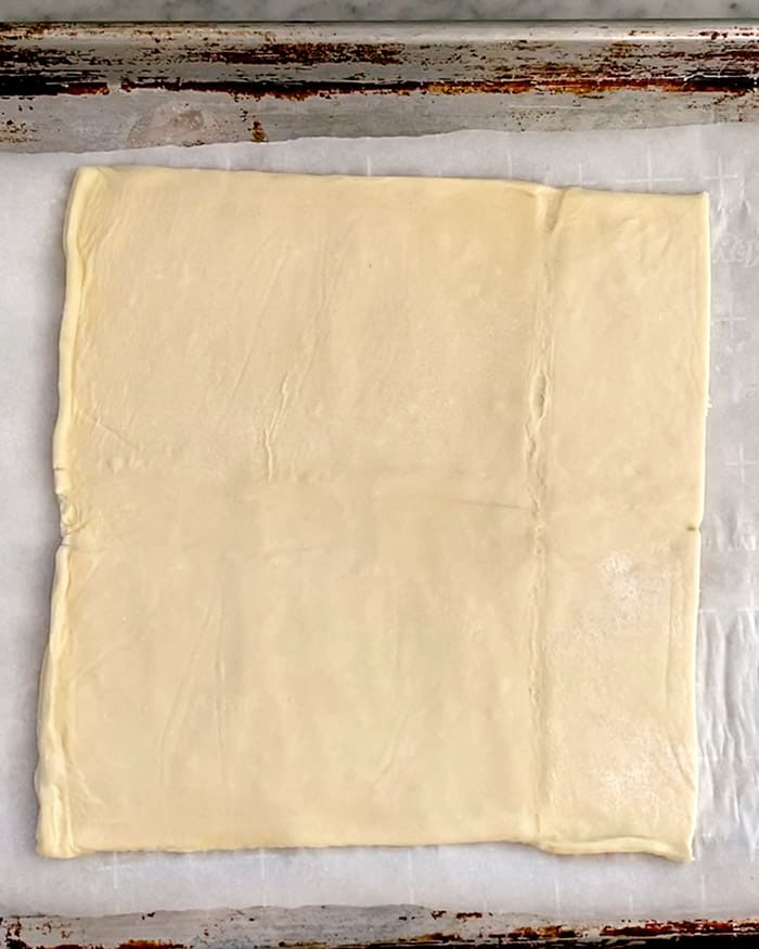 Raw puff pastry on a baking sheet.