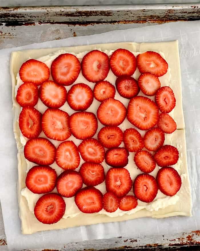 A puff pastry sheet layered with sliced strawberries. 