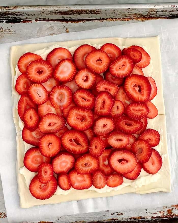 A puff pastry sheet layered with sliced strawberries. 