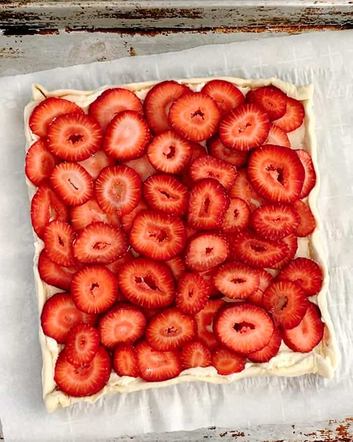 A puff pastry sheet layered with sliced strawberries. 