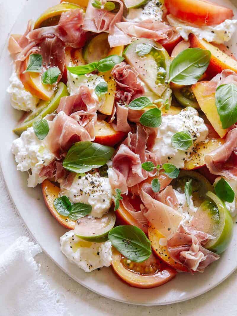a summer snack board with seasonal fruit and burrata.
