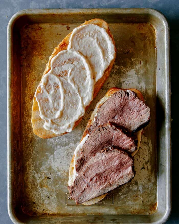 An open tri tip sandwich topped with fresh slices of tri tip.