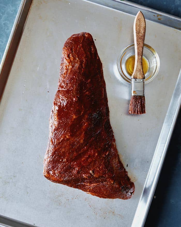 Unwrapped meat brushed with oil to prepare for being grilled.