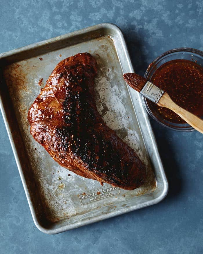 A seared tri tip that is being basted with the basting marinade.