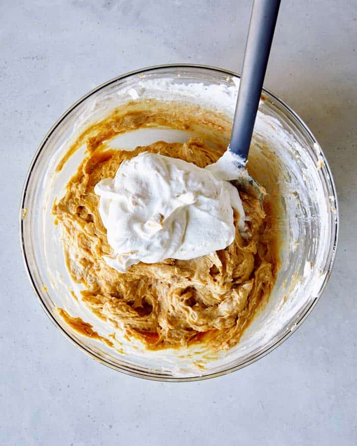 Adding more whipped cream into the creamy peanut butter pie filling.