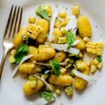 Summer corn gnocchi with corn and zucchini and a fork on the side.